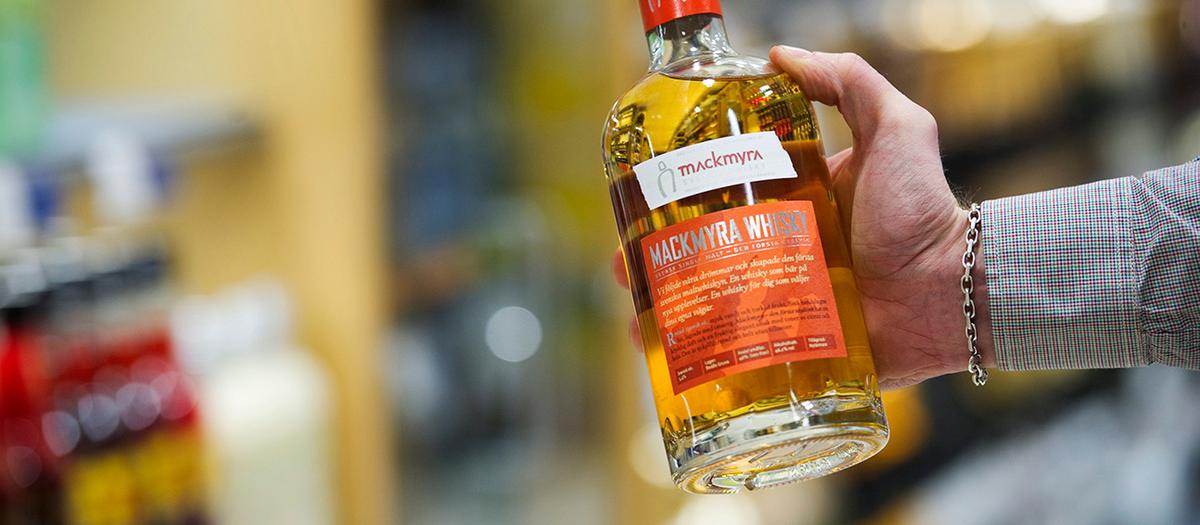 En bild på en hand som håller i en flaska whiskey från producenten Mackmyra.