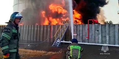 Två brandmän bekämpar en kraftig brand i en oljedepå i Azovdistriktet i Ryssland.