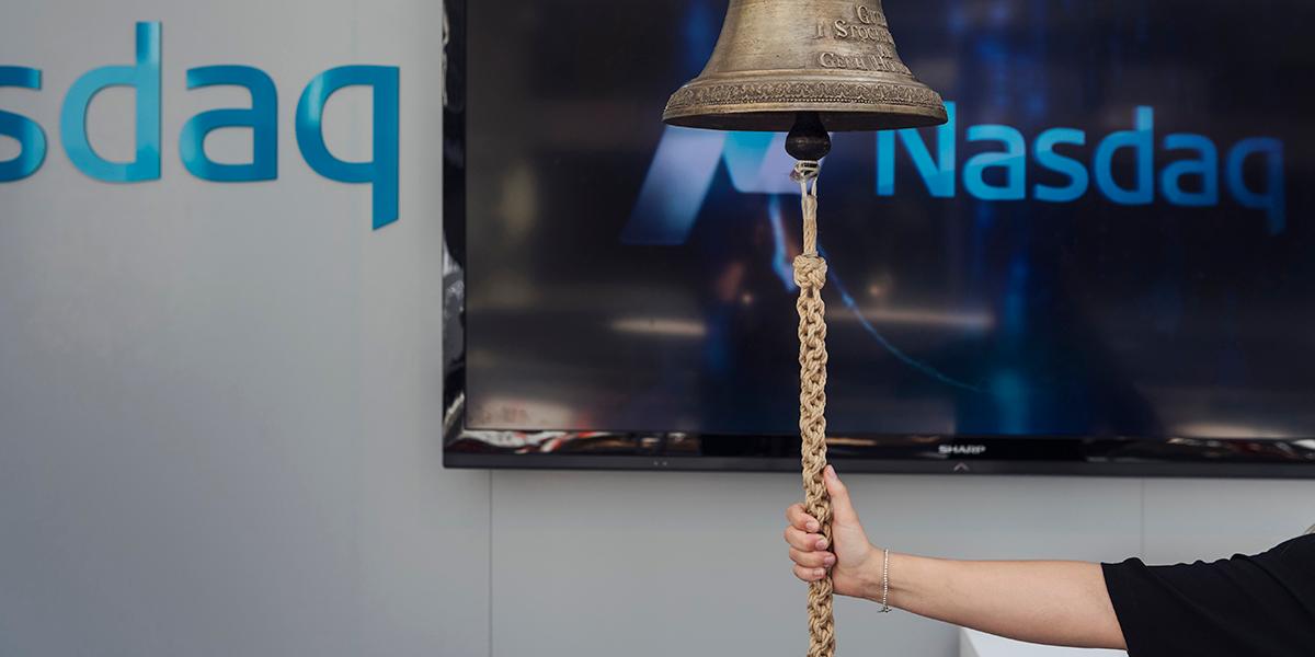 En person som ringer i klockan inne på Nasdaq-börsen i Stockholm.