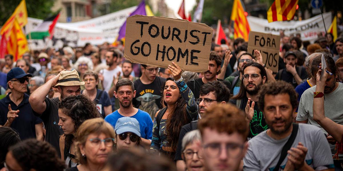 En bild på demonstranter i Barcelona med skyltar som säger "Tourists go Home".