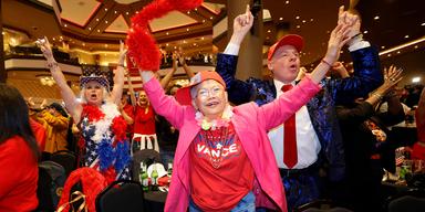 Trumpanhängare som firar valresultatet under en valvaka på ett hotell i Las Vegas. De är festklädda och de viftar glatt med armarna i luften.