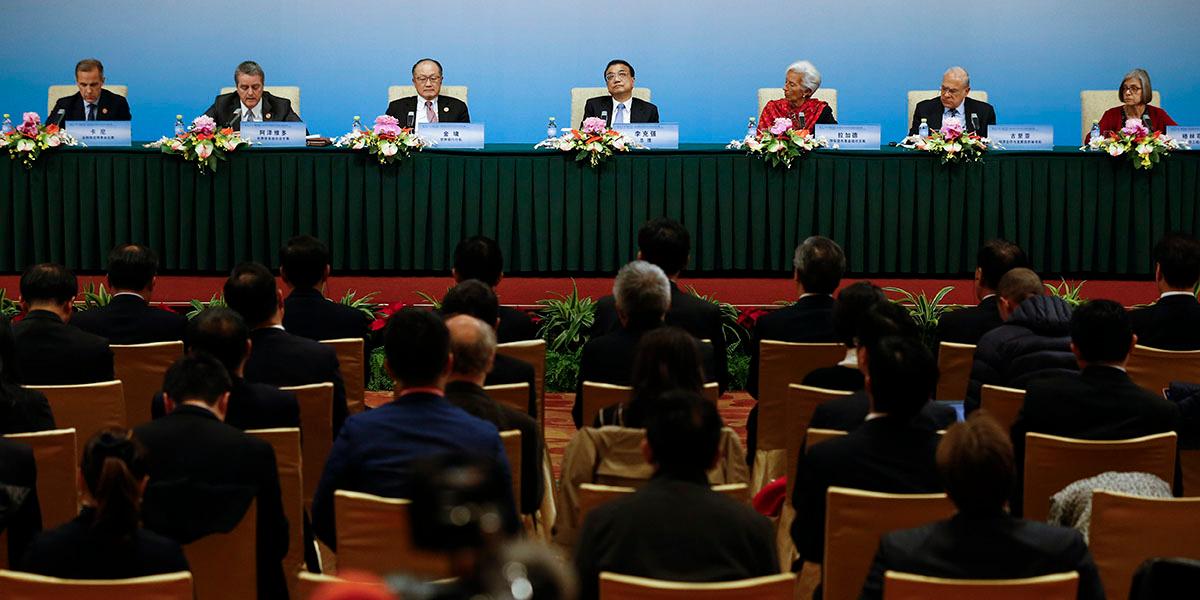 En bild från konferensen China World Economy där en publik sitte roch tittar på några talare vid ett podium.