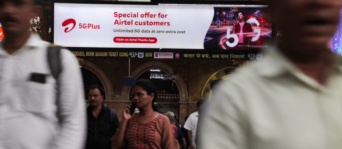 Pendlare går förbi en reklam för Airtel 5G Plus, på en järnvägsstation i Mumbai, Indien, 14 juni 2023. Foto: TT