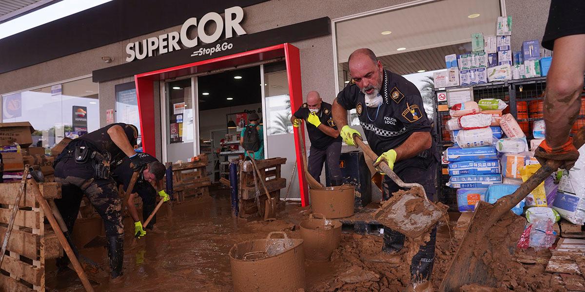 En bild på lokala polismän som öser brun lera i stora hinkar utanför en livsmedelsbutik.