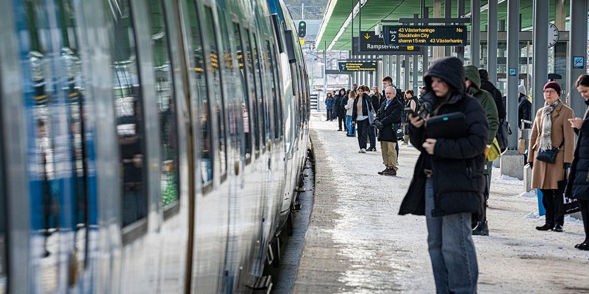 En bild på människor som står på perrongen vid ett pendeltåg.